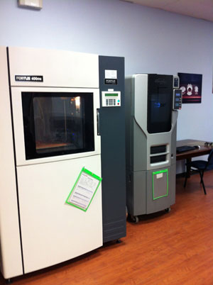 A Fortus 400mc 3D printer on the left. On the right: a Stratasys Dimension 3D printer.