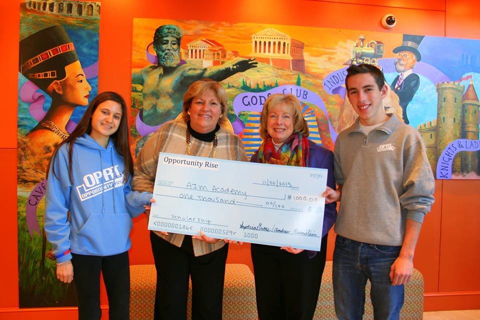 Opportunity Rise cofounders Sophia Gross (far left) and Andrew Rosenstein present a $1,000 check to their school, AIM Academy. The money will go toward a scholarship.