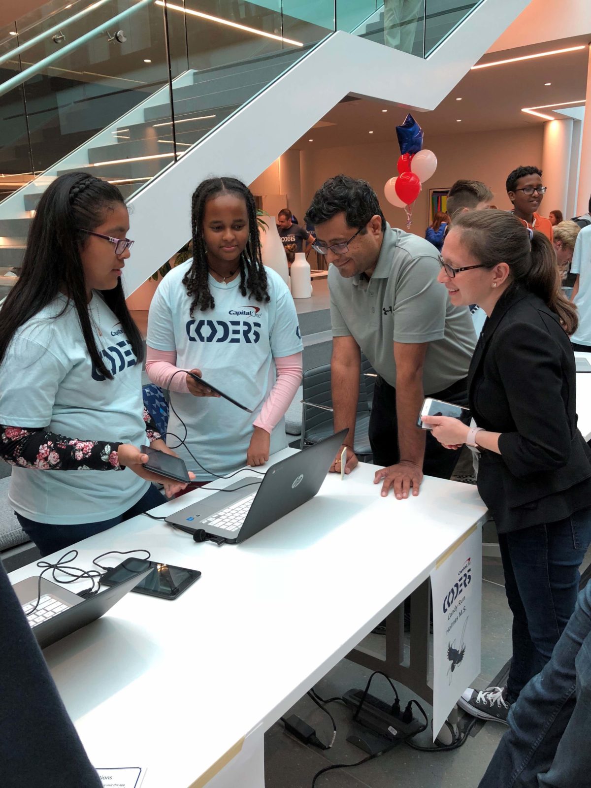Erika Dean and Rajiv Sondhi, Vice President of Software Engineering at Capital One, with students demonstrating their apps. (Photo courtesy of Capital One)