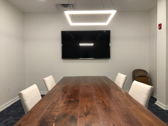 Conference room with a smooth mahogany table and a large screen television