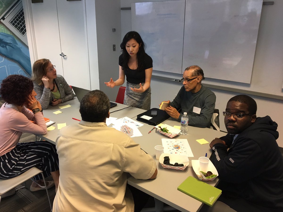 Ellen Hwang speaks to a group of workshop participants seated around a table.