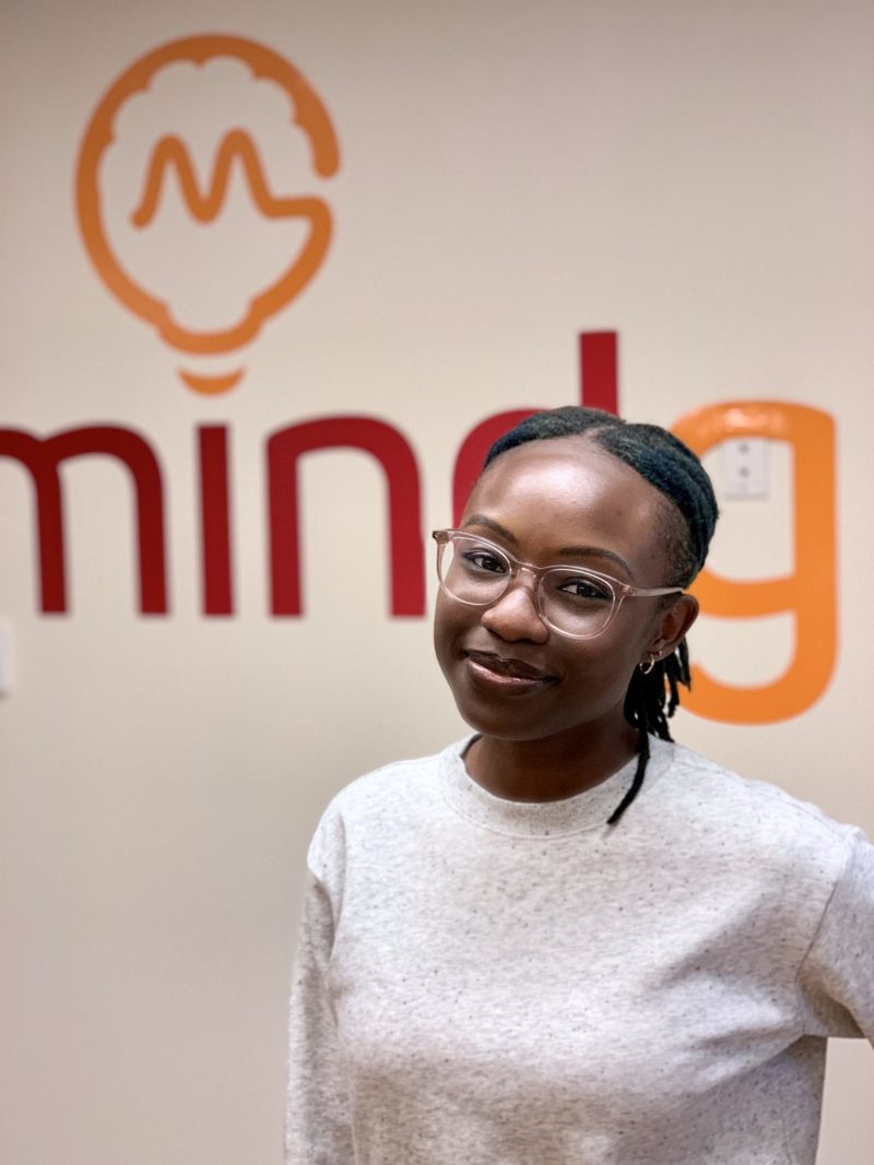picture of Sandra Koranteng standing in front of a Mindgrub sign