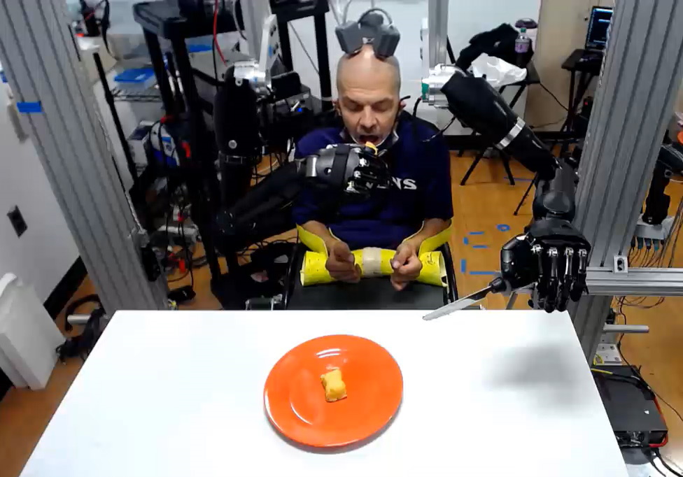Robert “Buz” Chmielewski using robot hands to eat.