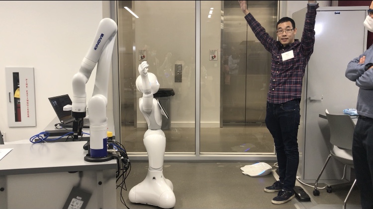 A CMU student demonstrates one of the space's robots mimicking human arm motion.