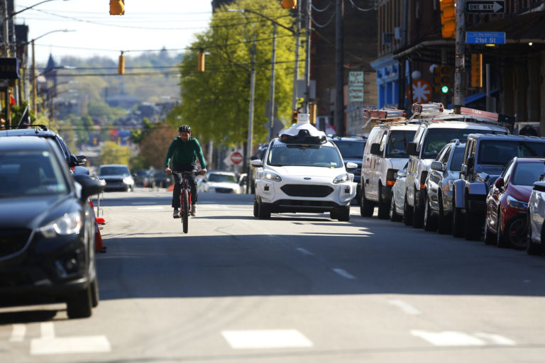 An Argo AI autonomous vehicle drives alongside a cyclist in Pittsburgh.