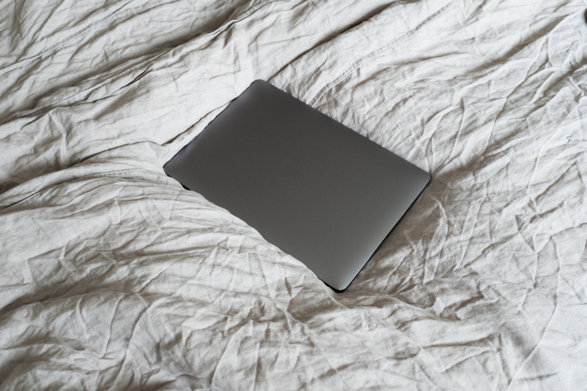 A closed laptop resting on a bed.