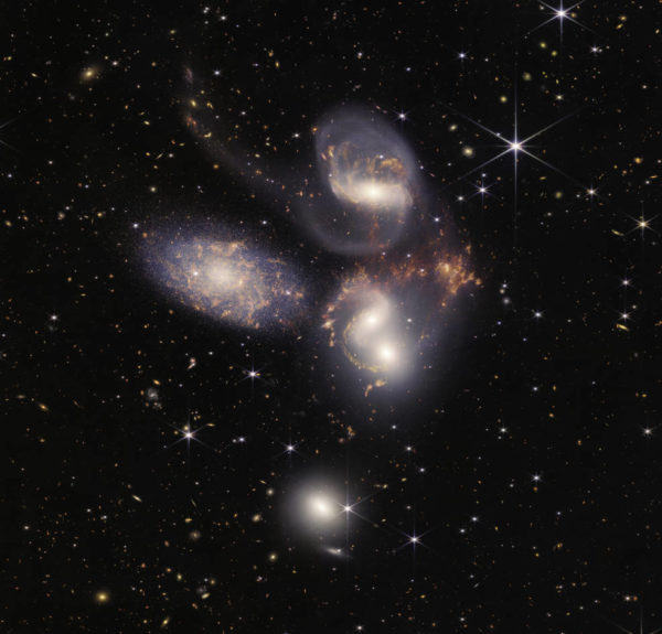 Five galaxies appear close to each other: two in the middle, one toward the top, one to the upper left, and one toward the bottom.