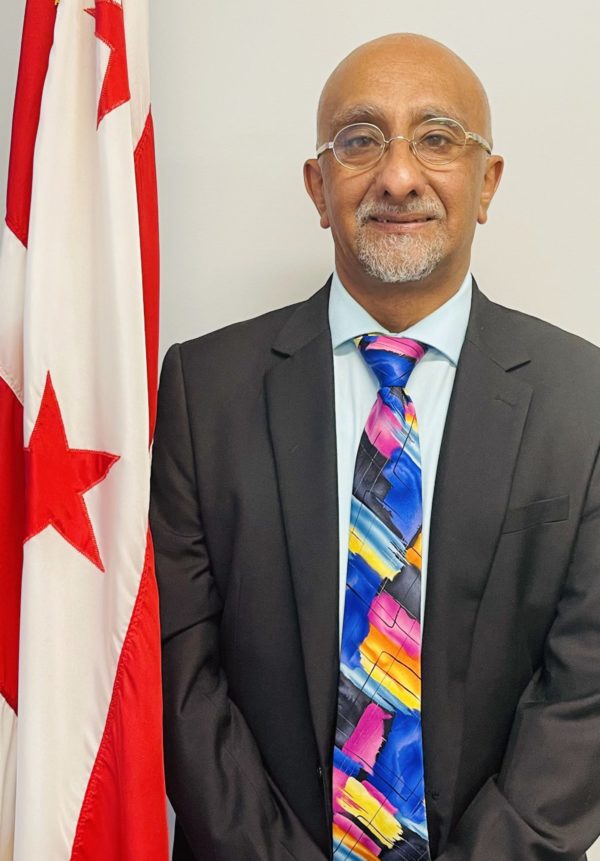 Dr. Anil Mangla stands next to the DC flag