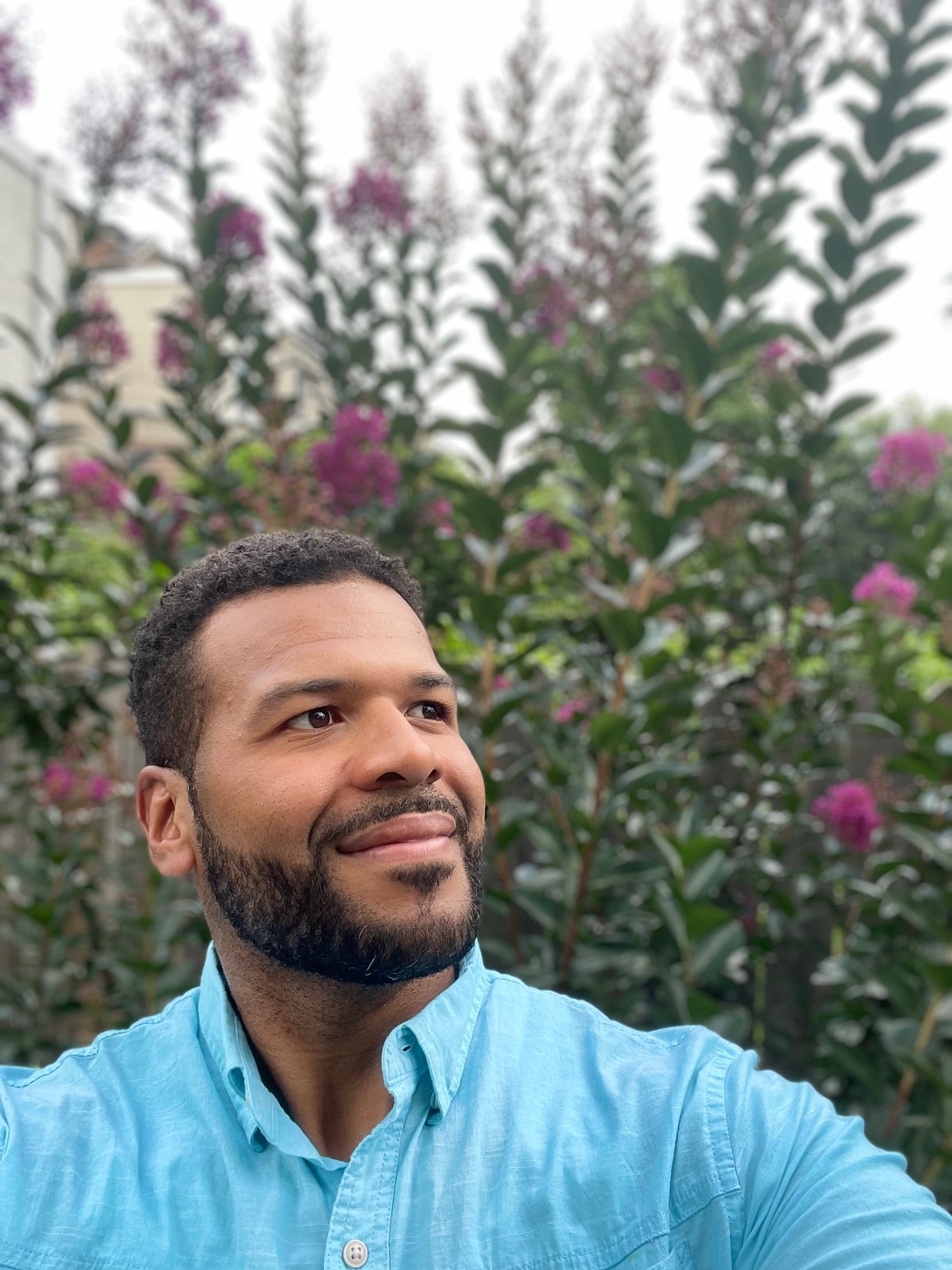 Orlando Perez in a blue shirt standing in front of flowers.