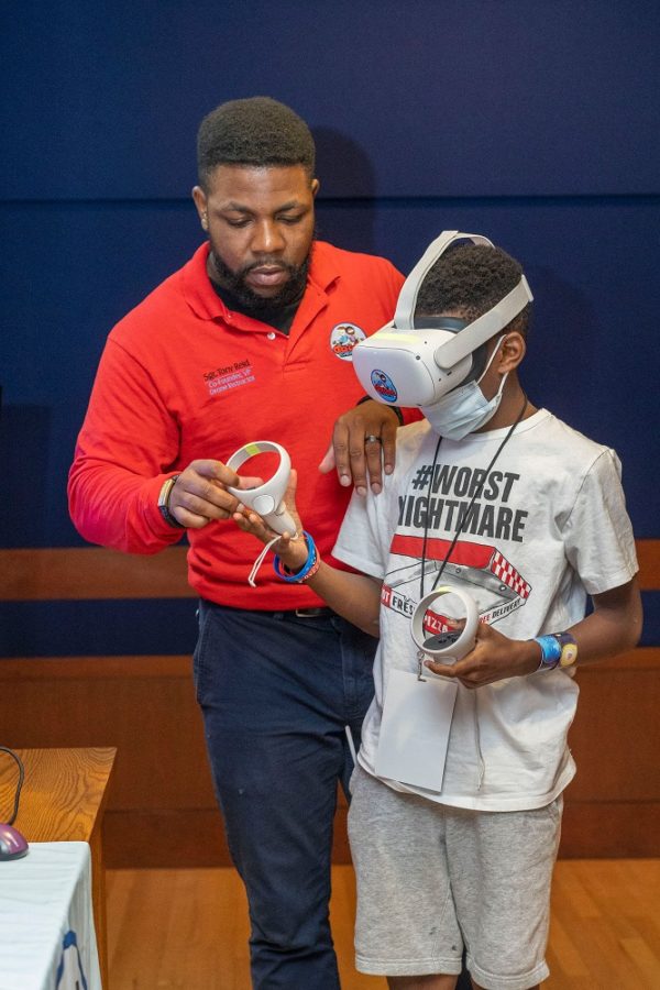 A man helps a kid use a VR headset.