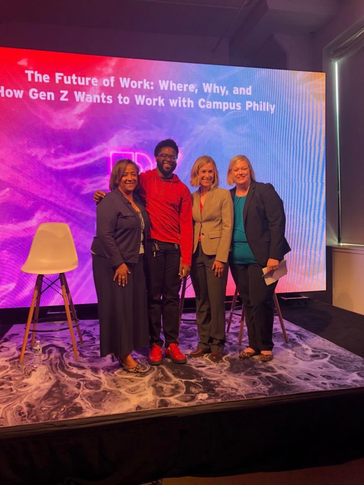 Four panelists stand in front of a colorful backdrop.