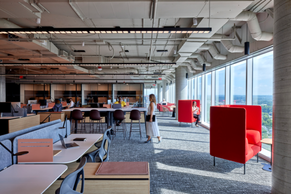 A workspace for employees with a communal table and comfy chairs overlooking the view from floor-to-ceiling windows.