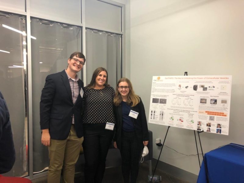 Will Brown, Erica Boetefuer and Julia Frederick pose next to a poster on an easel.