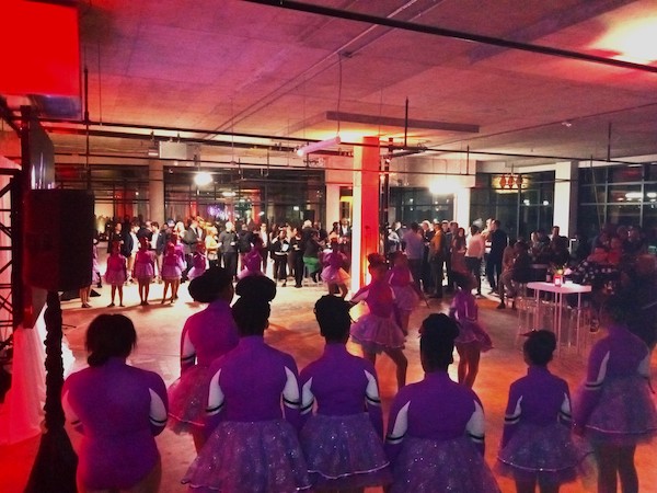 Girls in purple dresses surrounded by red light and people