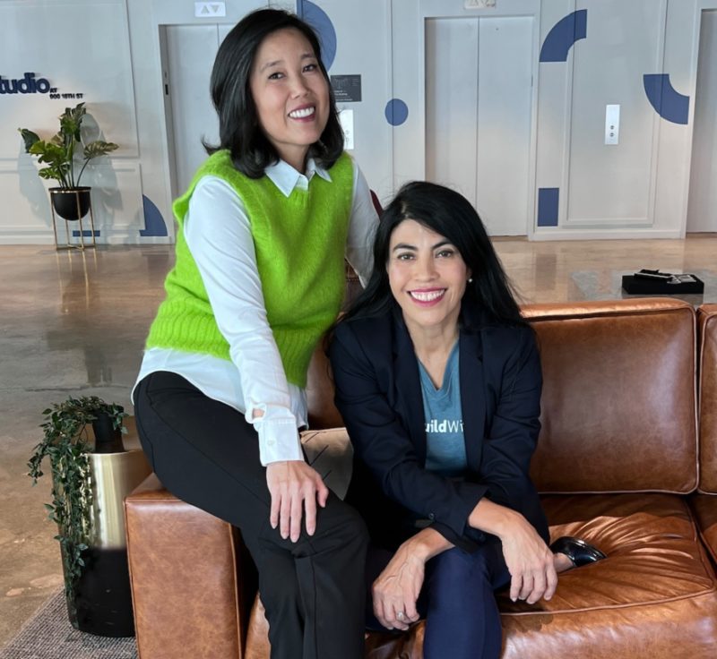 Two women sit on brown leather chair