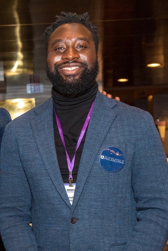A man wearing a suit and smiling at an event.