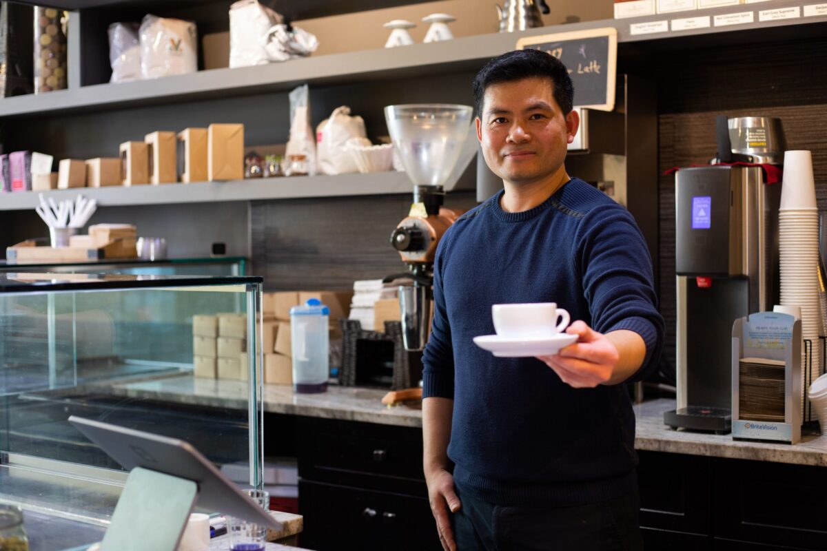 A man holding a cup of coffee in a coffee shop.