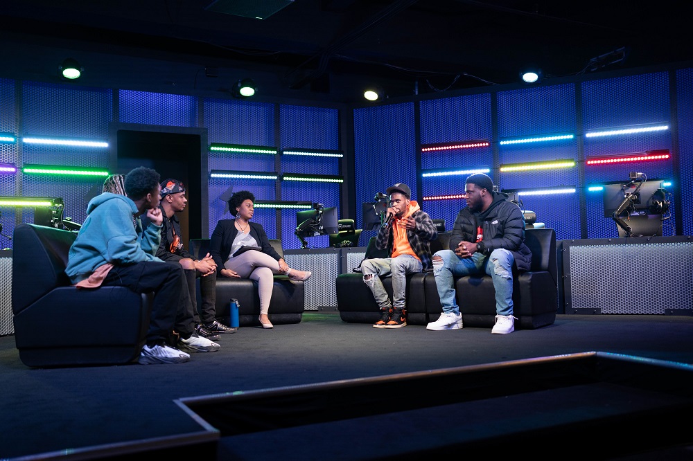 People sitting on a stage talking into a microphone.
