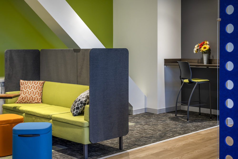 Lime green couch with dark brown enclosure near green walls and grey and brown floor