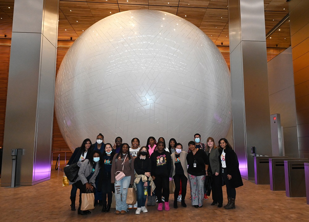 Students from HomeWorks standing in front of the globe at Comcast.