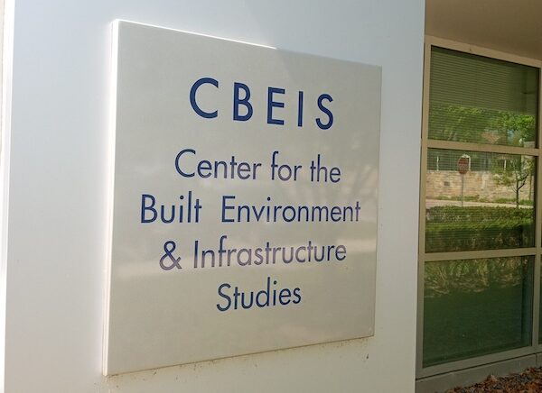 CBEIS sign with blue text and off-white background on white wall.