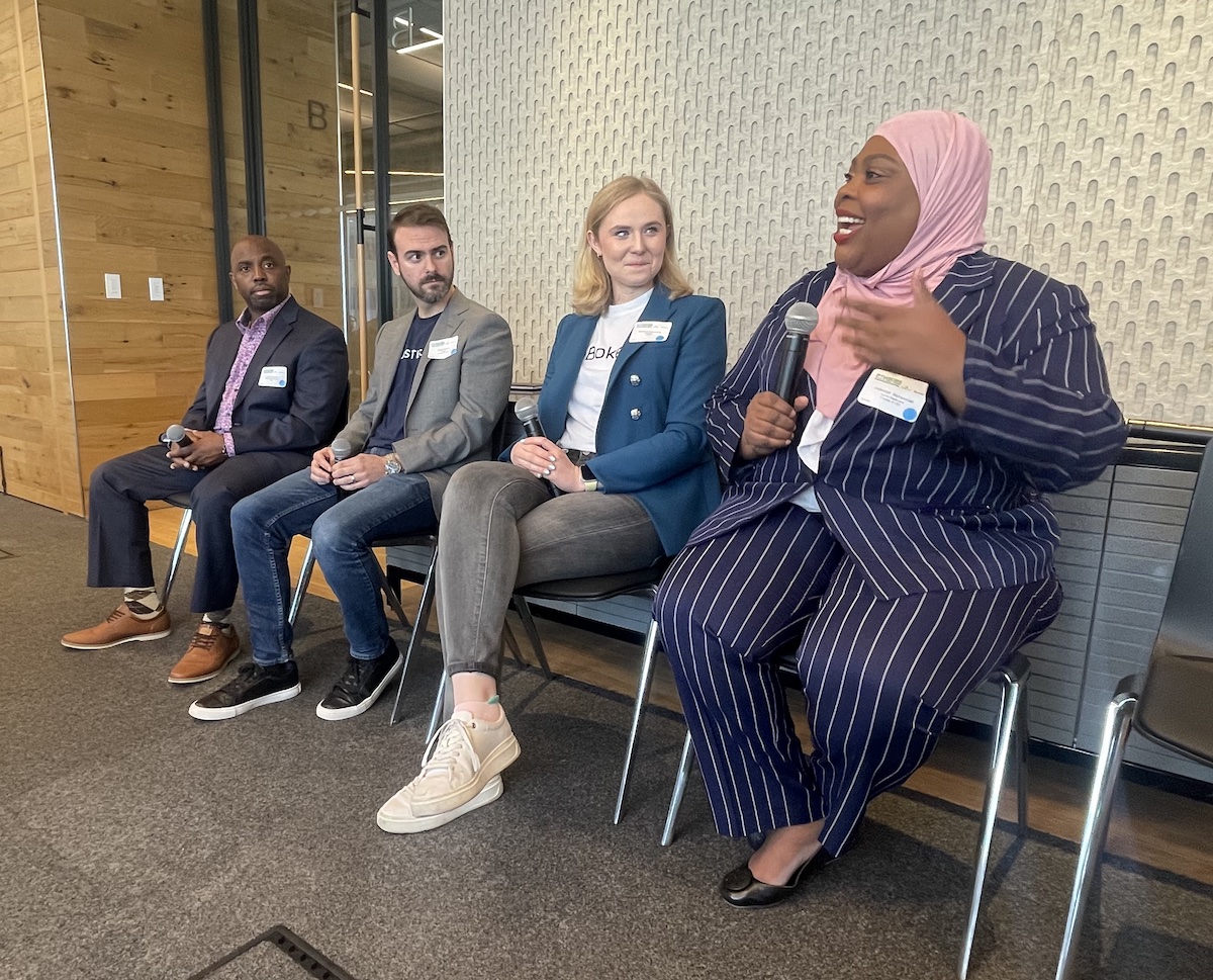 Four panelists sit in a row.