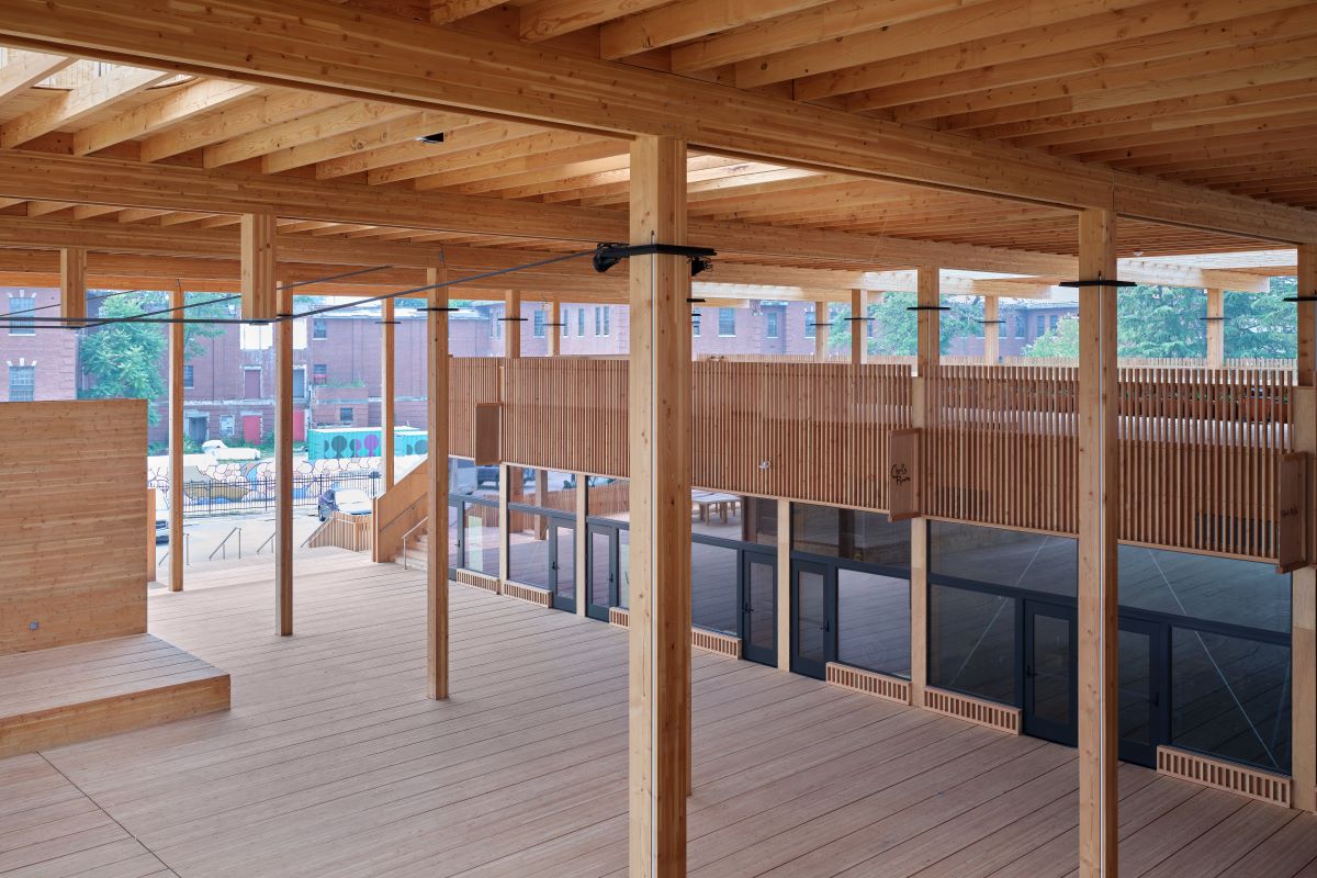 An open space featuring wooden polls and retail spaces on the side. 