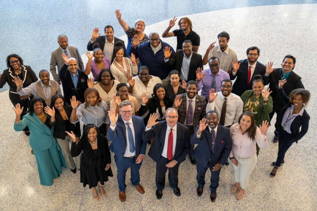 A group waves at a camera overhead during a June 2023 meeting between Agilent execs and Delaware State University.