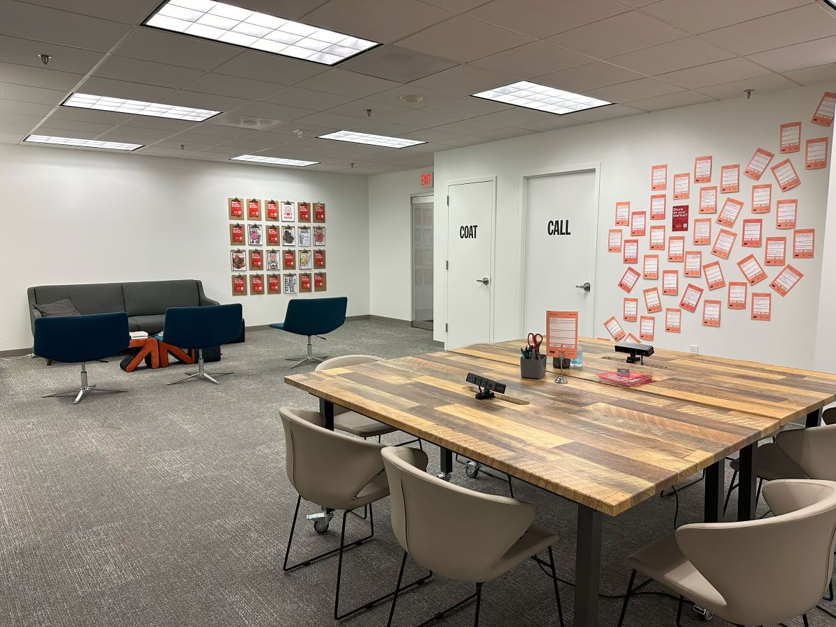 A table sits in the middle of the room with an orange mural on the wall. 
