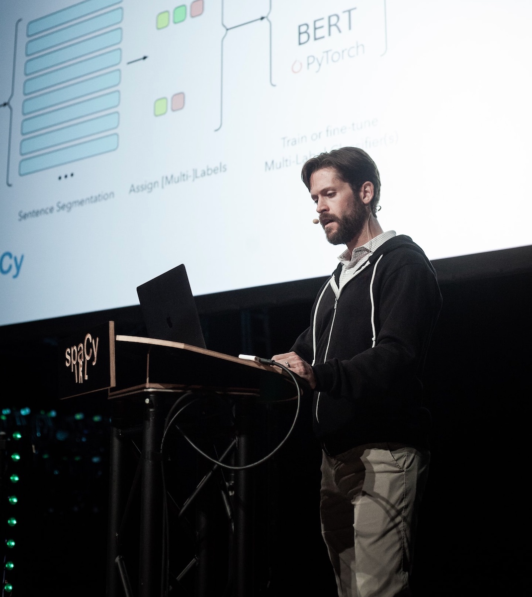 A man standing at a podium with a laptop in front of him.