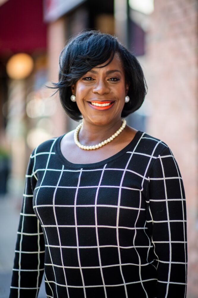 A woman smiling in front of a building.