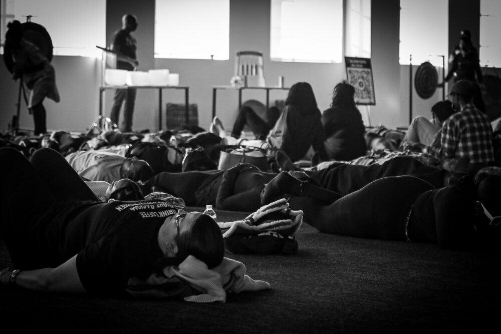 A black-and-white image of a group of people laying down on the floor.