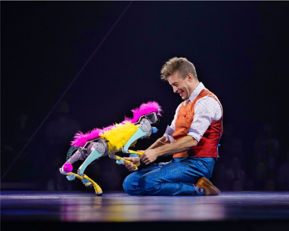 A man is playing with a robot animal on stage.