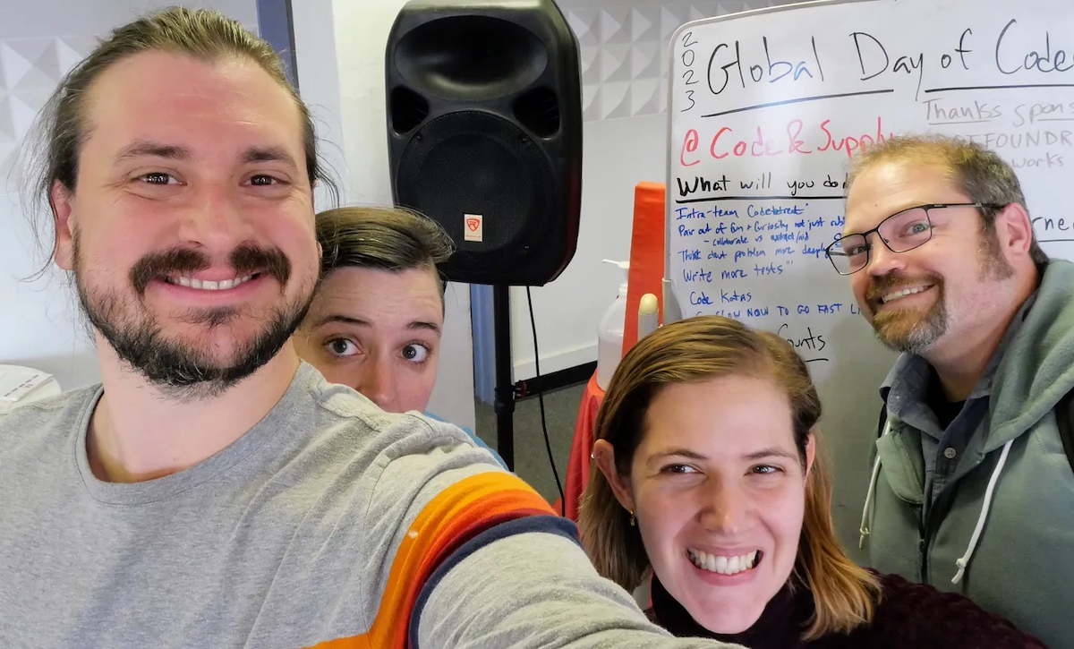 A group of people taking a selfie in front of a whiteboard.