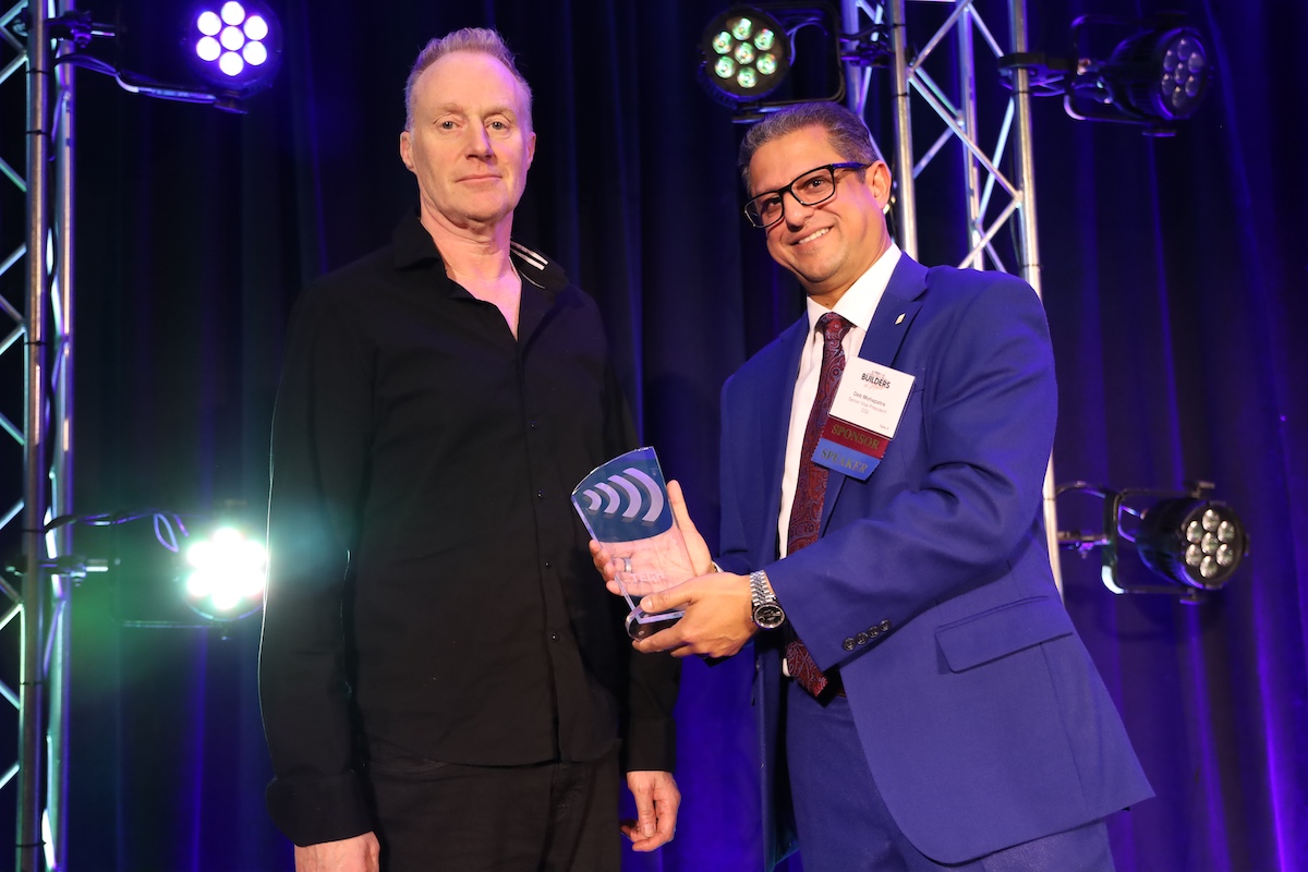 Two men standing next to each other holding an award.