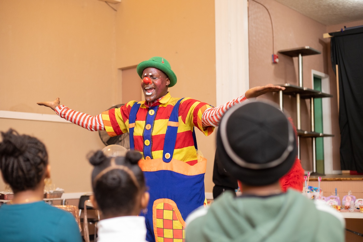 A clown is standing in front of a group of children.