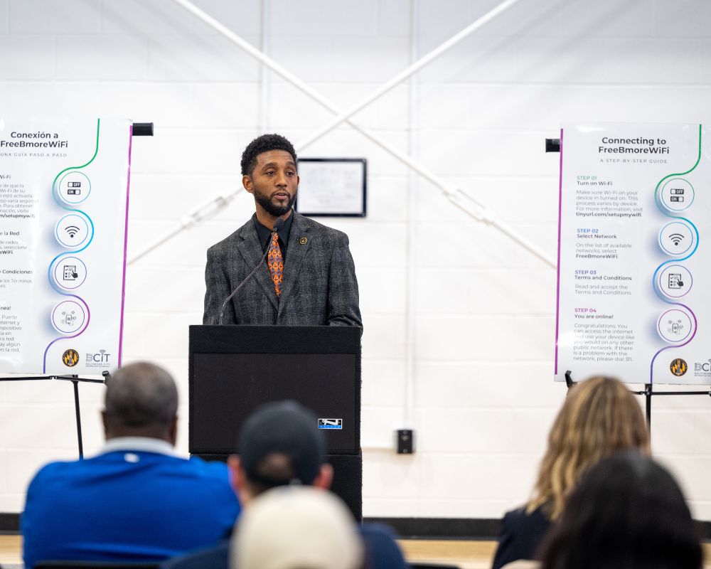 Brandon Scott stands at a podium in front of a group of people.