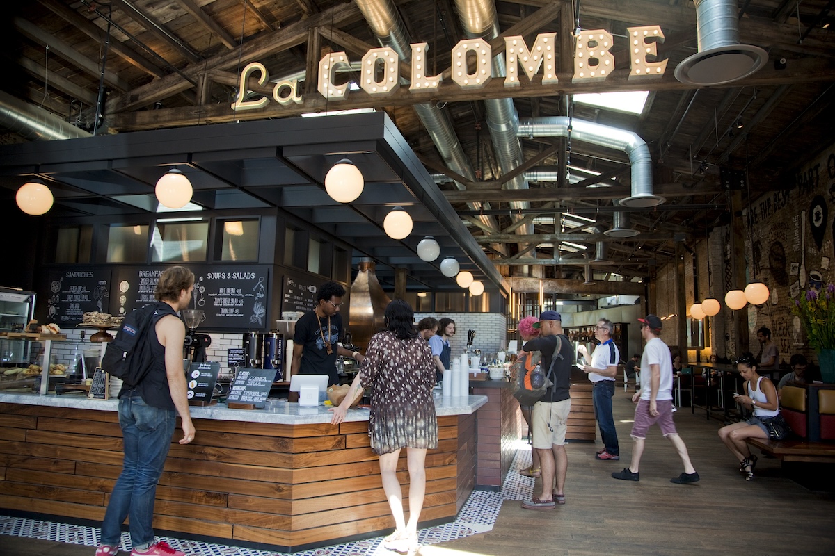 A group of people standing in front of a coffee shop with a sign that says la colombe.