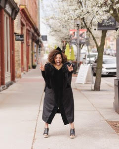 Jen Fry in black outfit near red building facades