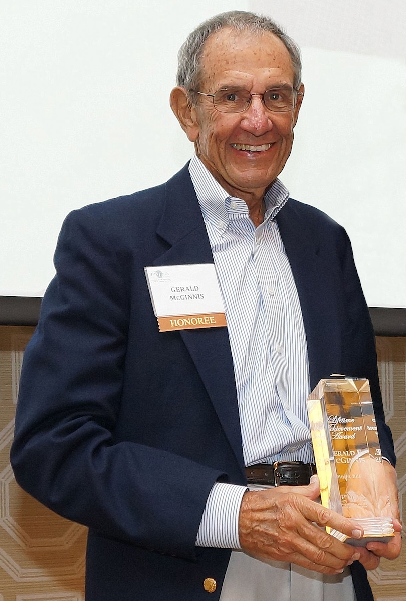 A smiling man in a blazer holding an award.