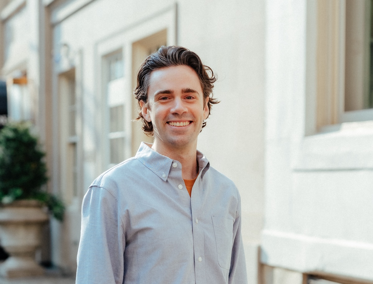 A man smiling in front of a building.