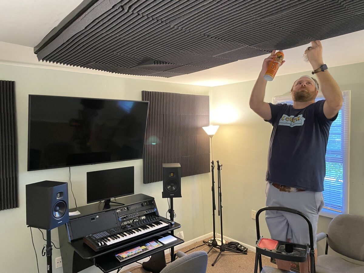 A man installing acoustic ceiling panels in a recording studio.