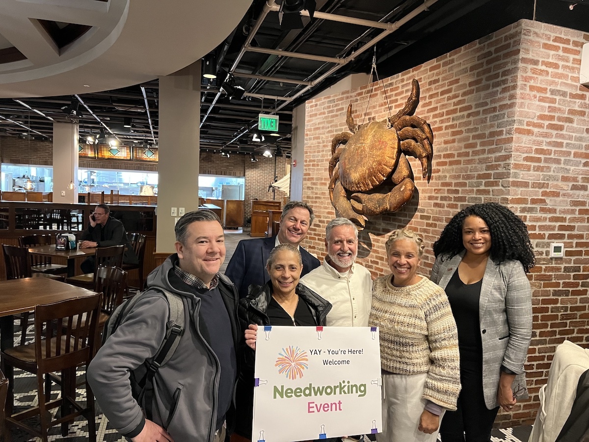 Dave Carberry, Shervonne Cherry and others at event holding Needworking event sign