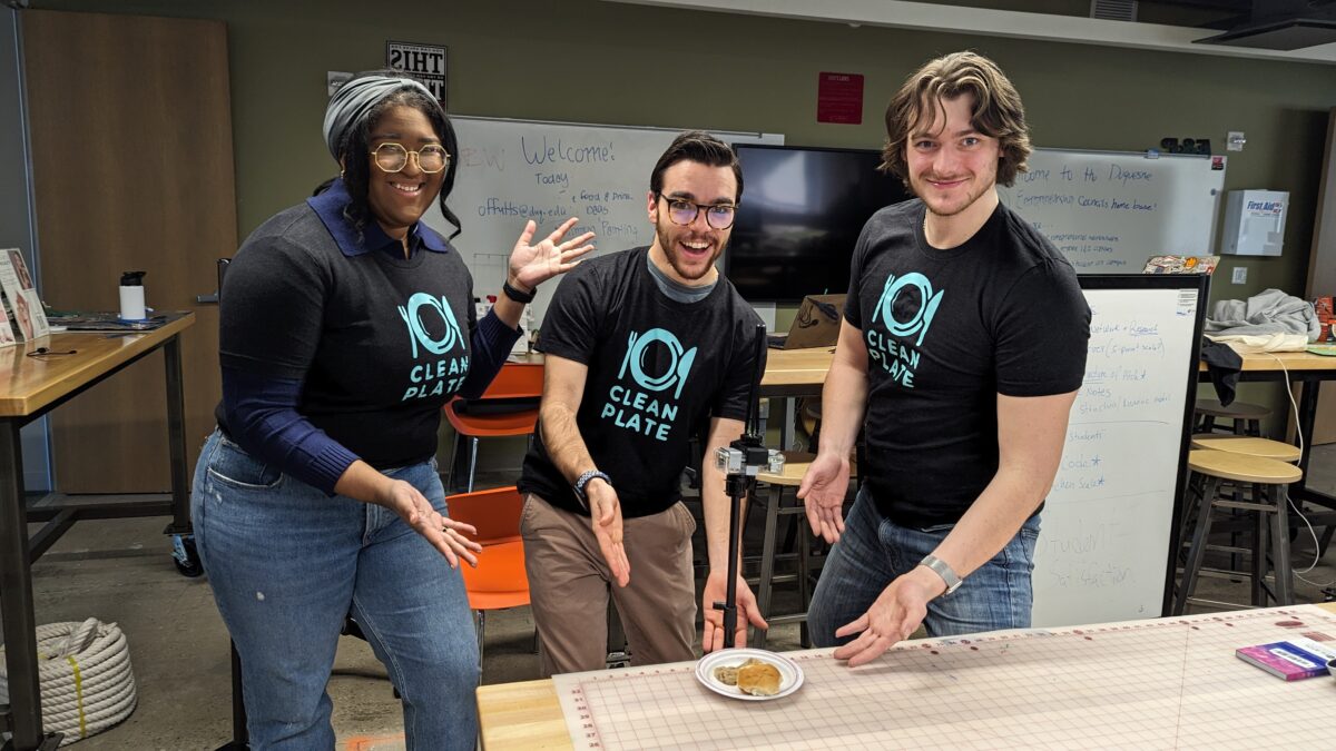 Three people posing in front of a table with food on it at Pittsburgh’s first Techstars Startup Weekend.
