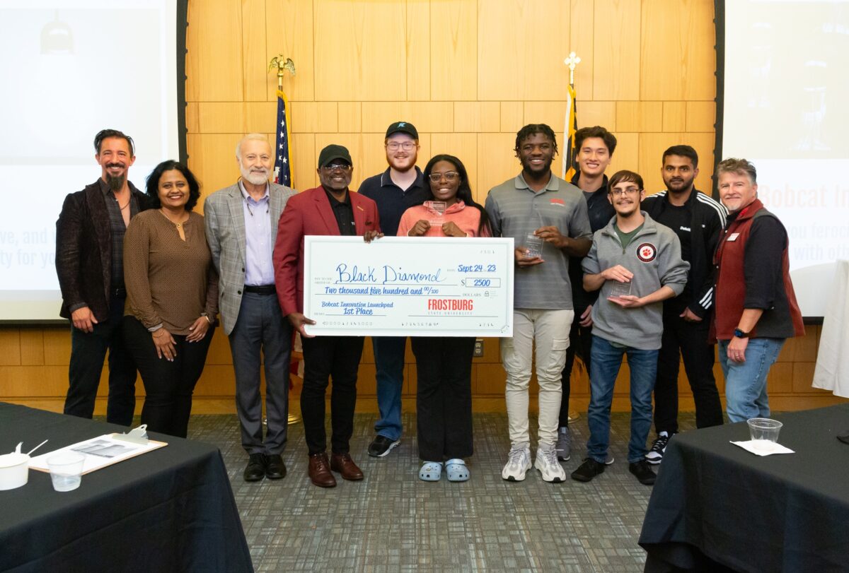 A group of students and event organizers posing with an oversized check.