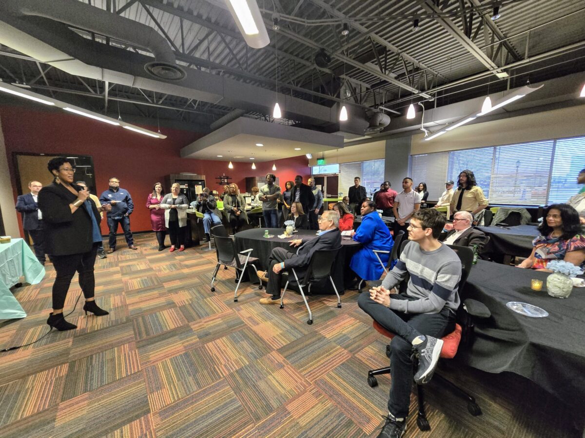 A speaker addressing an attentive audience in an indoor event space.