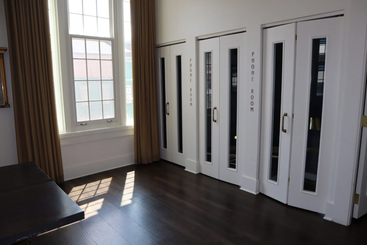 A row of doors labeled "phone room" and large windows letting in sunlight.