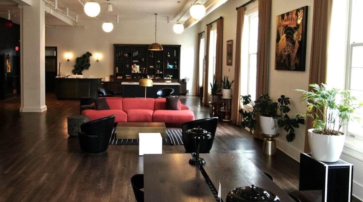 Modern coworking lounge area, with red sofas, wooden floors, and decorative plants.