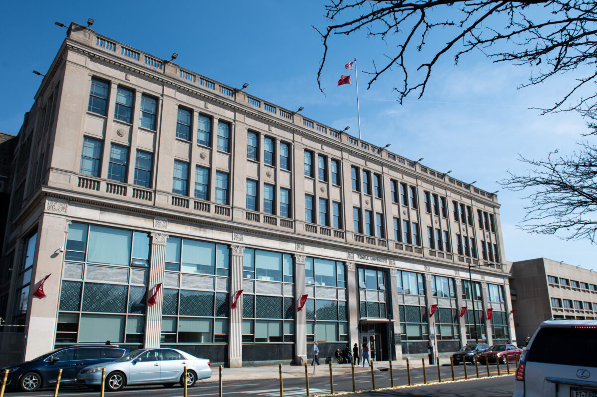 A large, multi-story classical building with canadian flags flying, viewed on a clear day.