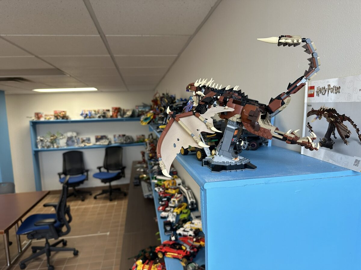 A detailed lego model of a scorpion displayed on a blue shelf in a room filled with various lego sets and collectibles.